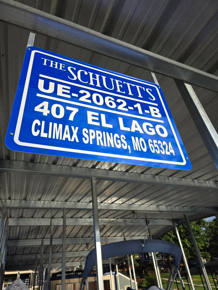 The Schuett’s · Dock Identification — A blue-and-white family dock sign, photographed in its covered-dock installation.